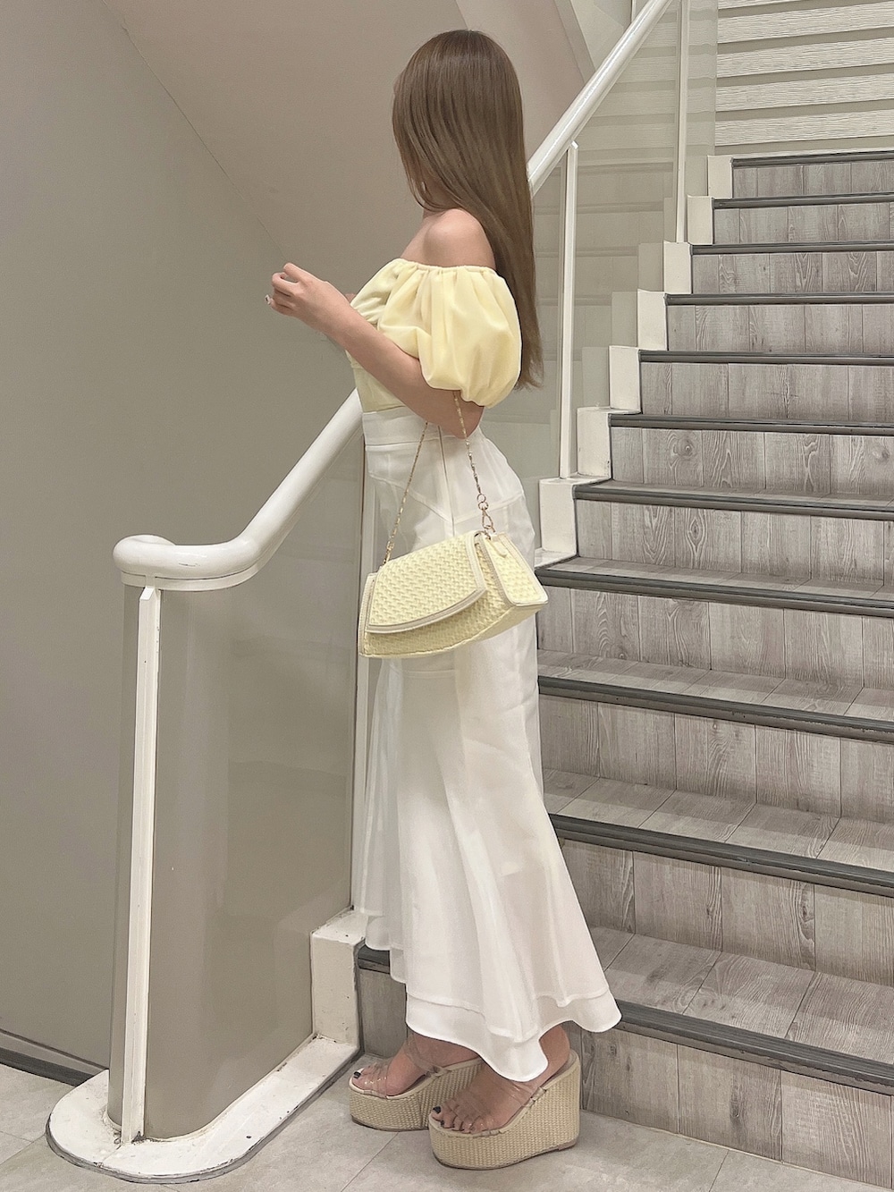 イエロー系のシャツ/ブラウス、ホワイト系のスカート、イエロー系のハンドバッグを着用したレディースの春コーディネートの3枚目の写真