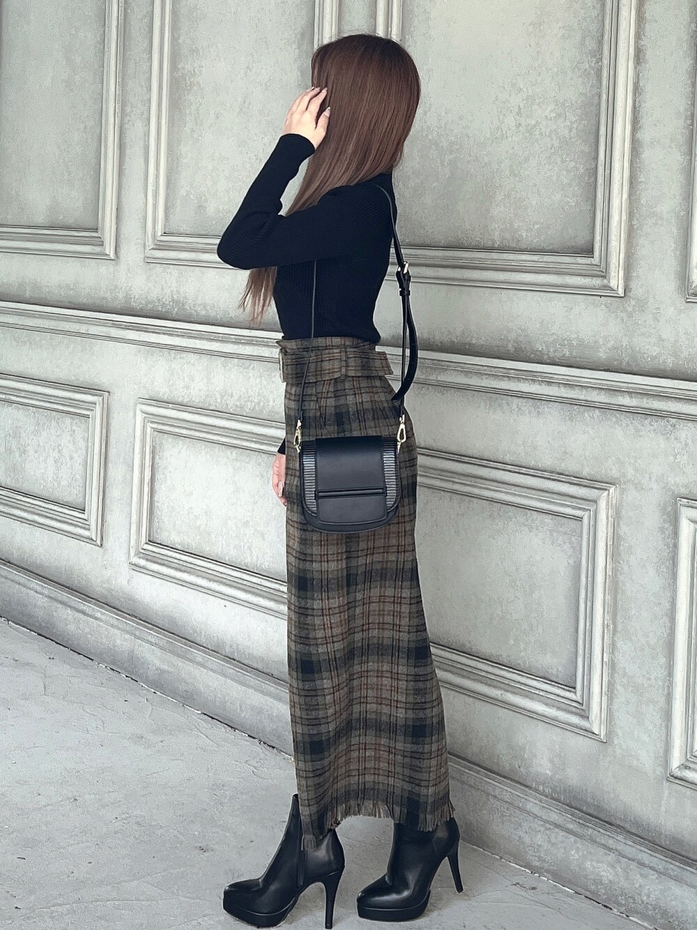 ブラック系のニット/セーター、グリーン系のスカート、ブラック系のショルダーバッグを着用したレディースの秋コーディネートの3枚目の写真