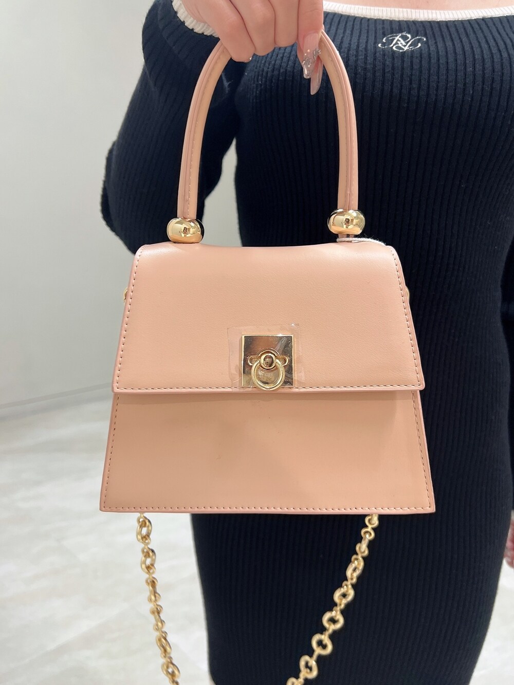 ブラック系のワンピース、ブラック系のブーツ、ピンク系のハンドバッグを着用したレディースの冬コーディネートの7枚目の写真