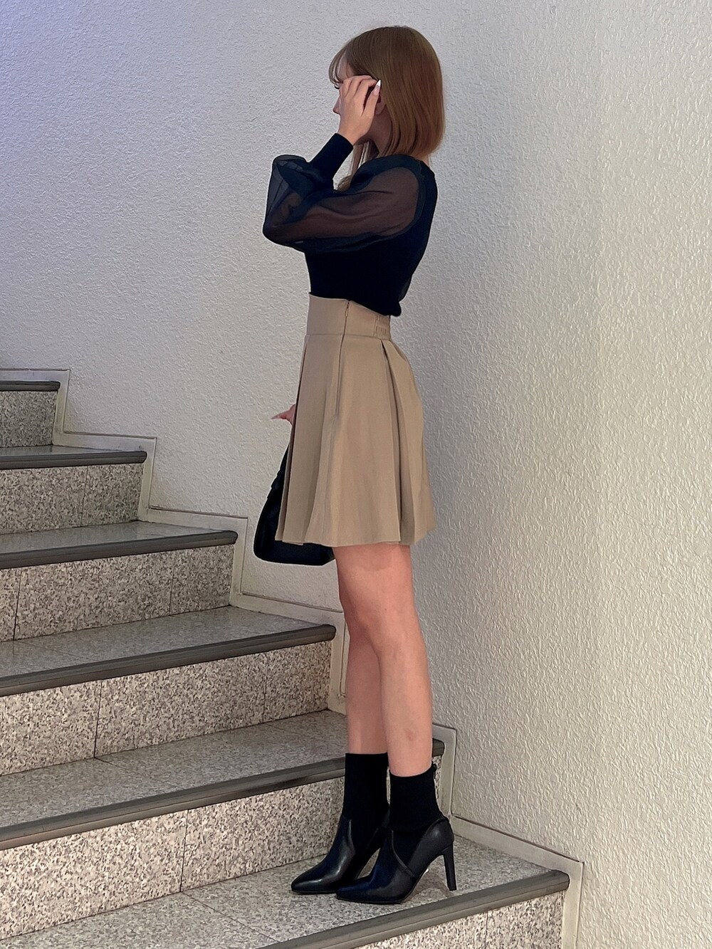 ブラック系のニット/セーター、ブラック系のハンドバッグ、ベージュ系のスカートを着用したレディースの冬コーディネートの4枚目の写真