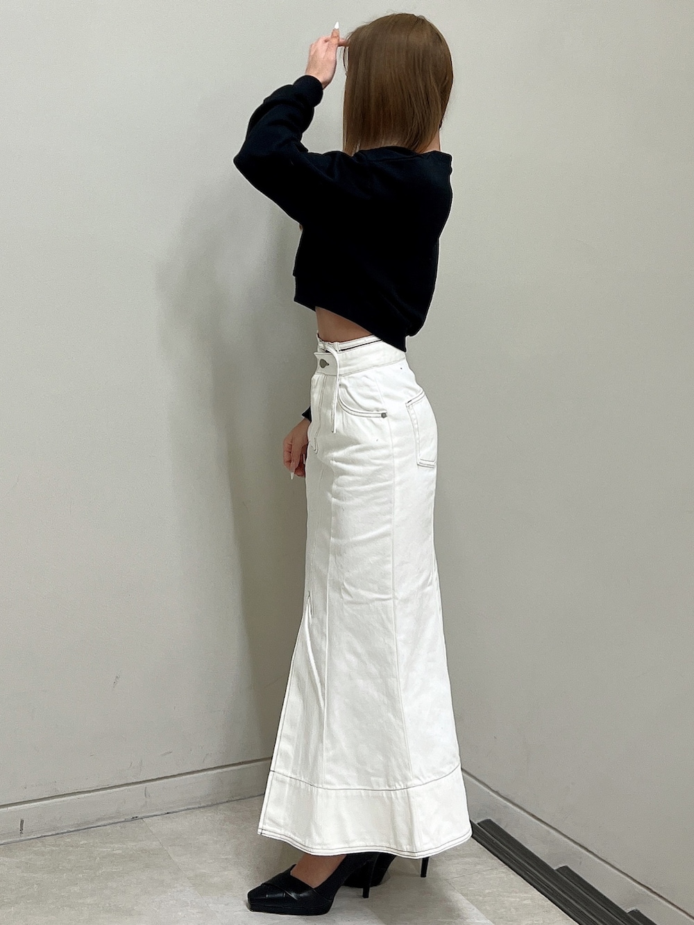 ブラック系のスウェット、ホワイト系のデニムスカート、ブラック系のパンプスを着用したレディースの冬コーディネートの3枚目の写真