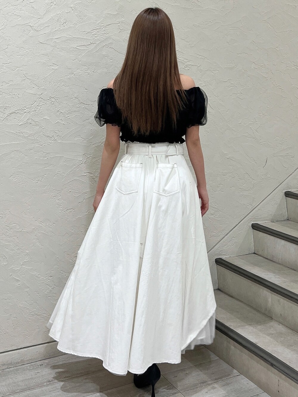 ブラック系のシャツ/ブラウス、ホワイト系のデニムスカート、ブラック系のパンプスを着用したレディースの春コーディネートの4枚目の写真