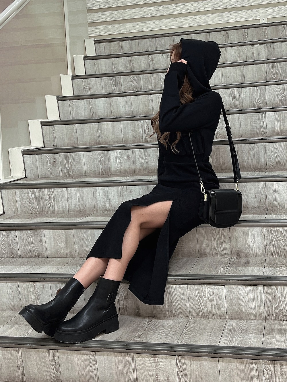 ブラック系のブーツ、ブラック系のショルダーバッグ、ブラック系のワンピースを着用したレディースの秋コーディネートの3枚目の写真