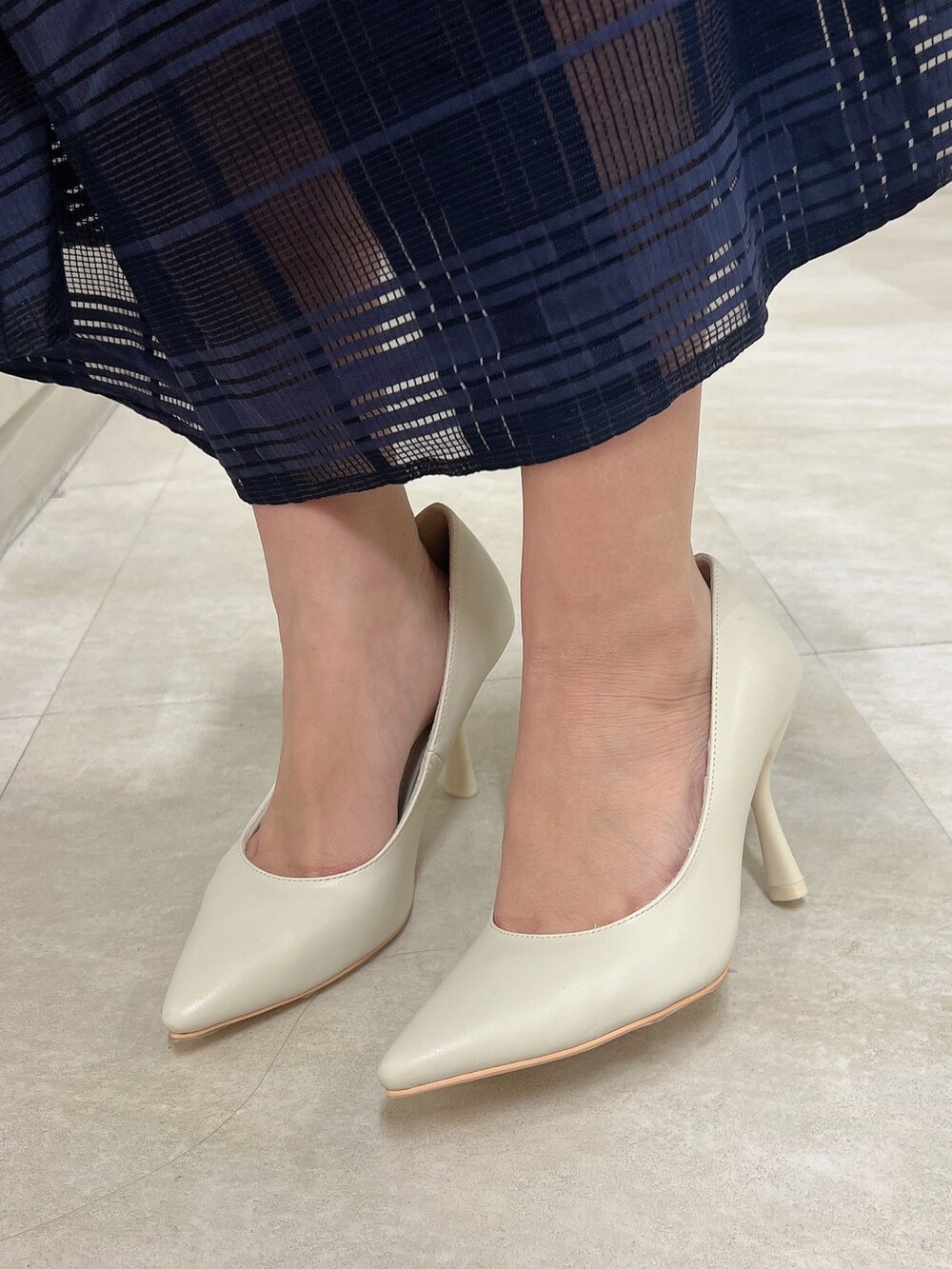 ホワイト系のパンプス、ブルー系のワンピース、ホワイト系のハンドバッグを着用したレディースの冬コーディネートの9枚目の写真