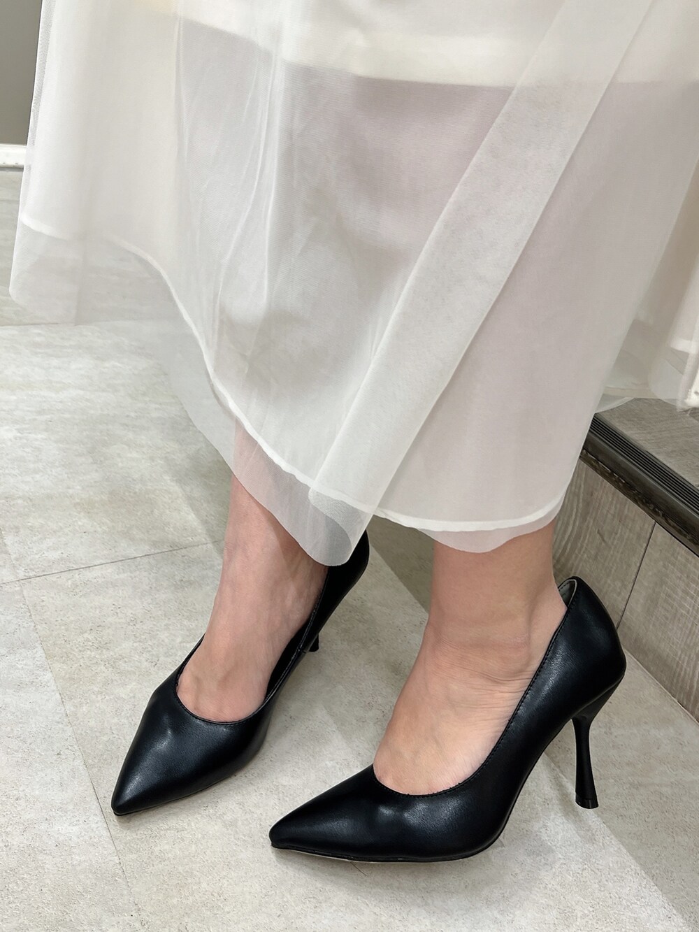 ブラック系のシャツ/ブラウス、ホワイト系のデニムスカート、ブラック系のパンプスを着用したレディースの春コーディネートの8枚目の写真