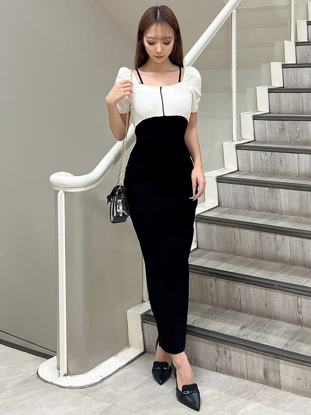 ブラック系のハンドバッグ、ホワイト系のワンピース、ブラック系のパンプスを着用したレディースの春コーディネートの2枚目の写真