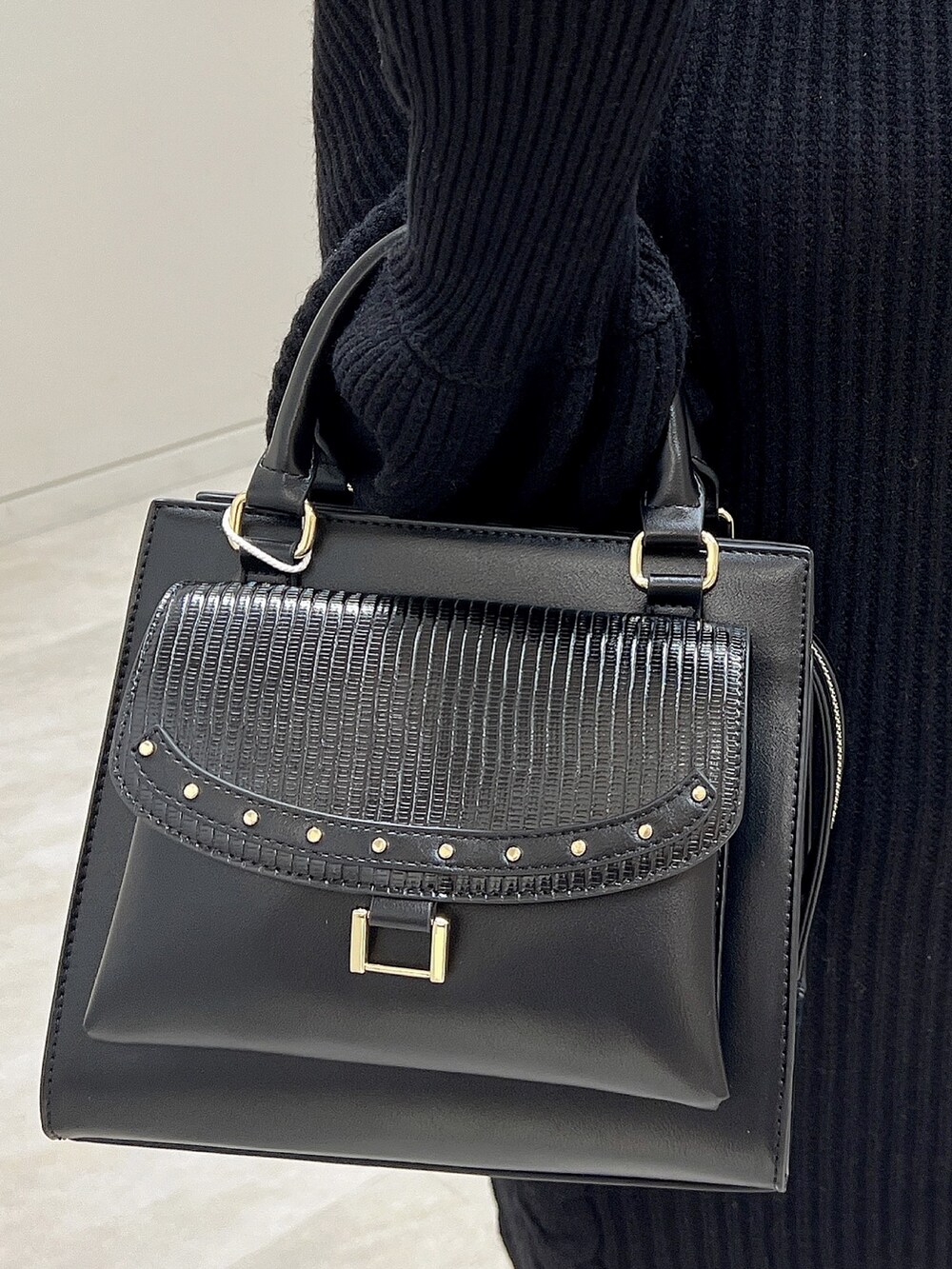 ブラック系のワンピース、ブラック系のブーツ、ブラック系のハンドバッグを着用したレディースの秋コーディネートの5枚目の写真