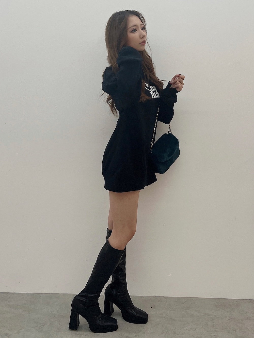 ブラック系のスウェット、グリーン系のハンドバッグ、ブラック系のブーツを着用したレディースの夏コーディネートの3枚目の写真