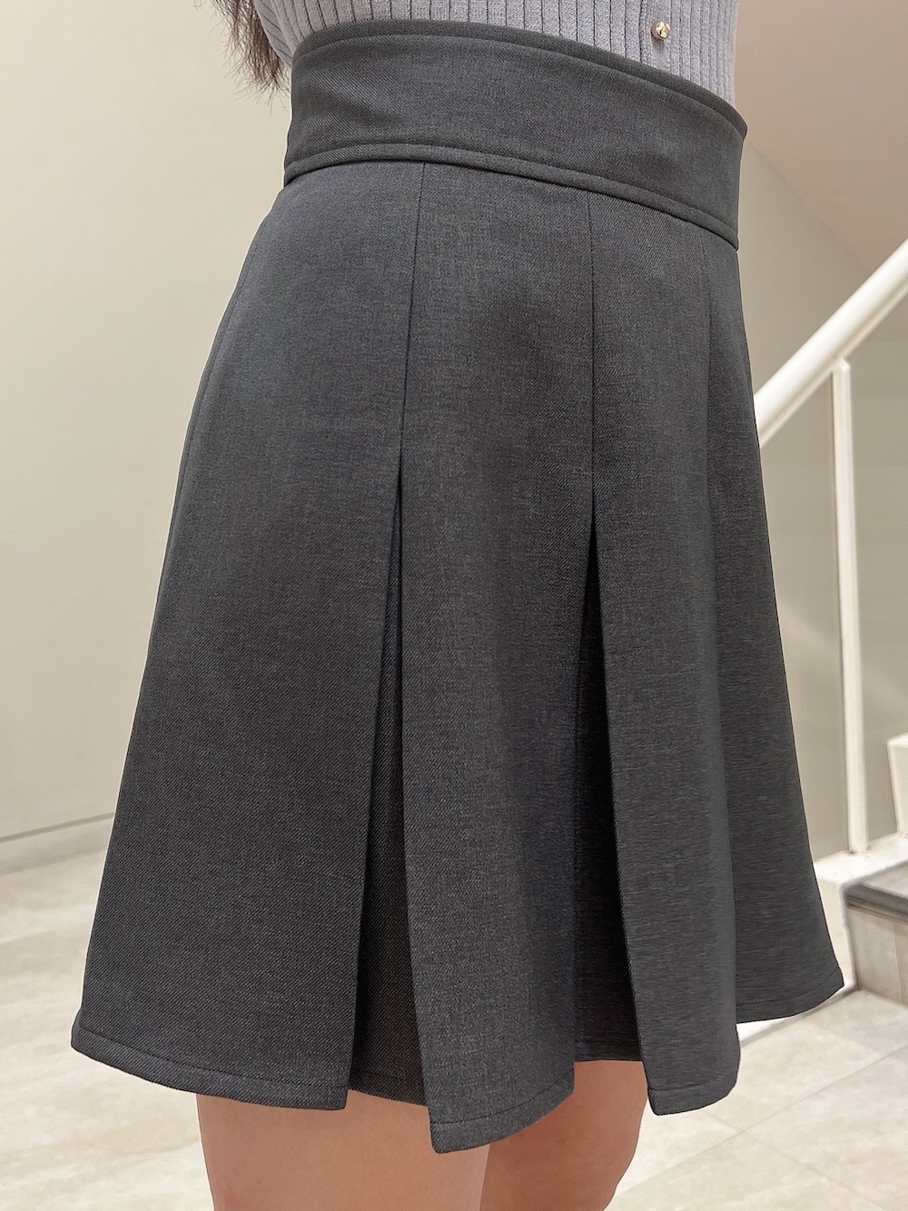 ブルー系のニット/セーター、グレー系のスカート、ブラック系のハンドバッグを着用したレディースの春コーディネートの6枚目の写真