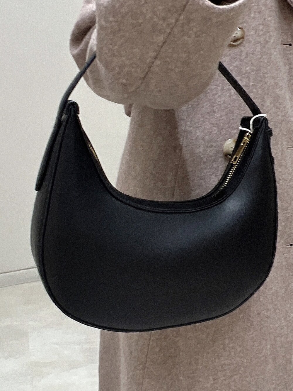 ブラウン系のチェスターコート、ブラウン系のブーツ、ブラック系のニット/セーターを着用したレディースの冬コーディネートの7枚目の写真