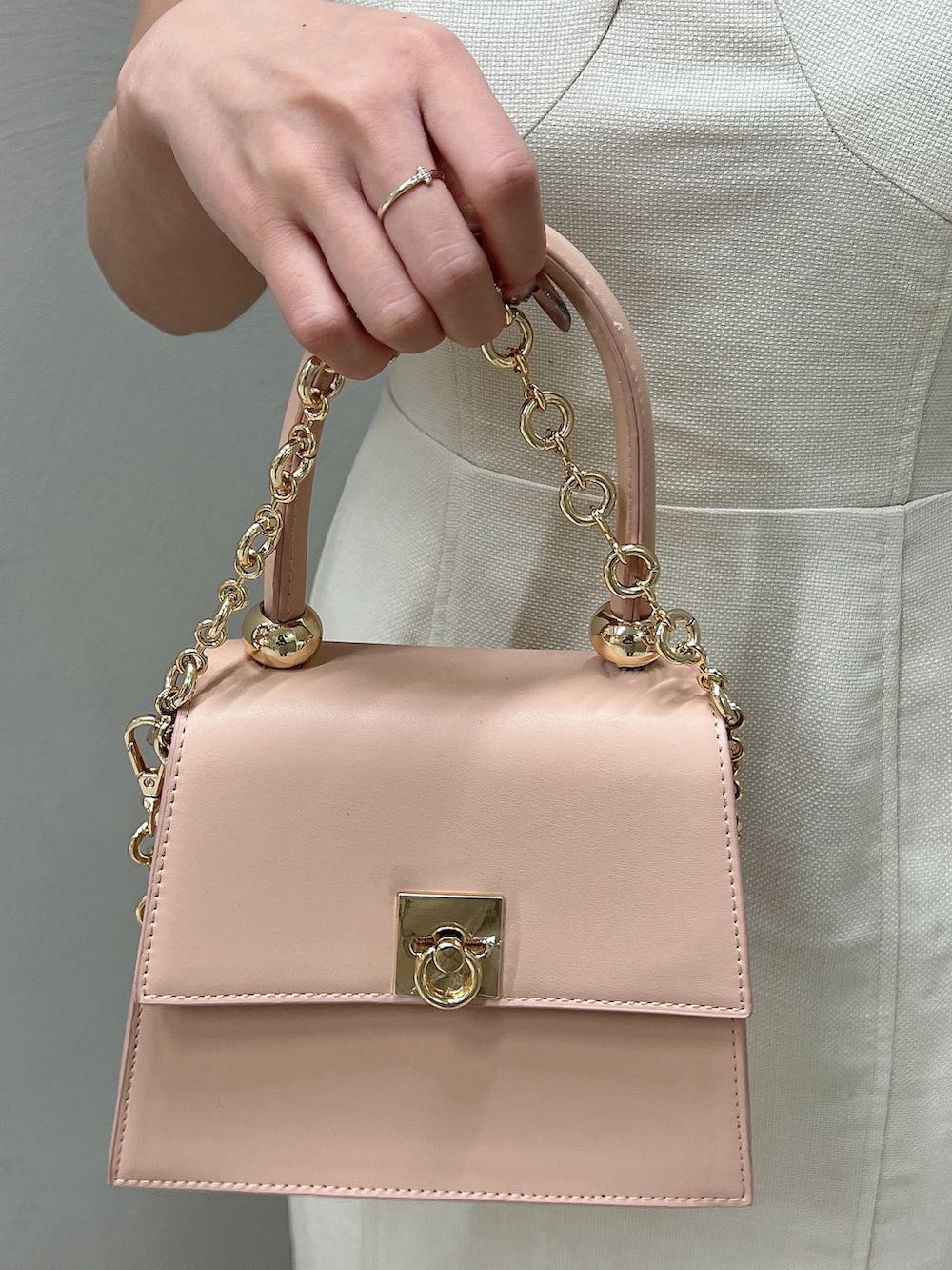 ホワイト系のパンプス、ホワイト系のワンピース、ピンク系のハンドバッグを着用したレディースの春コーディネートの6枚目の写真