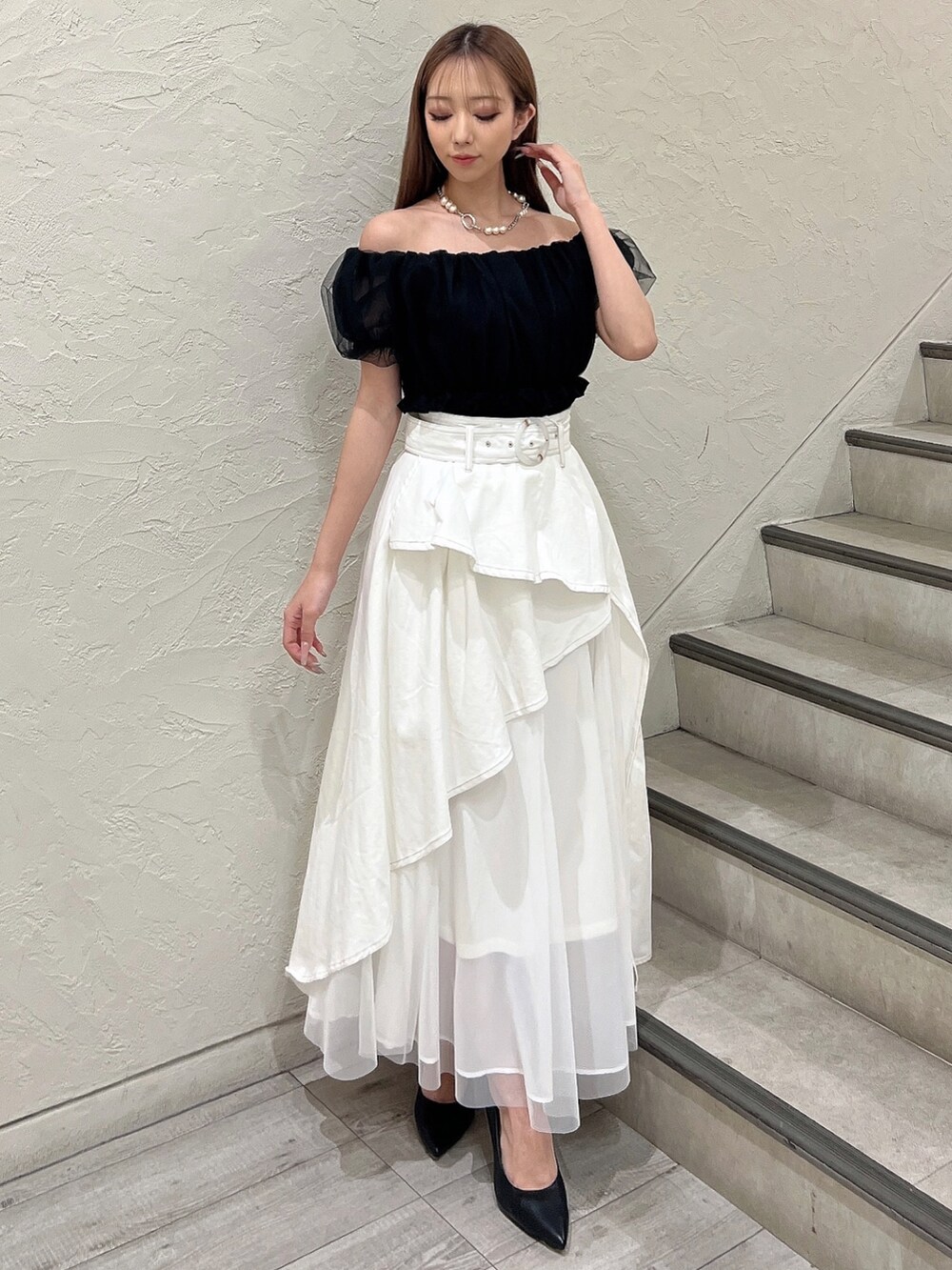 ブラック系のシャツ/ブラウス、ホワイト系のデニムスカート、ブラック系のパンプスを着用したレディースの春コーディネートの2枚目の写真