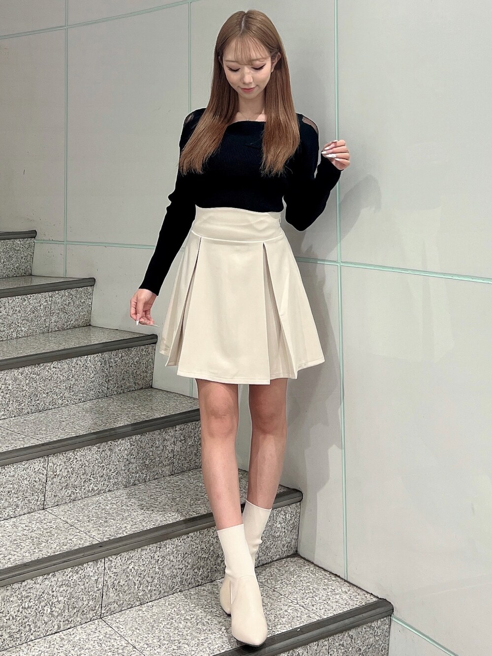 ホワイト系のライダースジャケット、ホワイト系のスカート、ブラック系のニット/セーターを着用したレディースの冬コーディネートの3枚目の写真