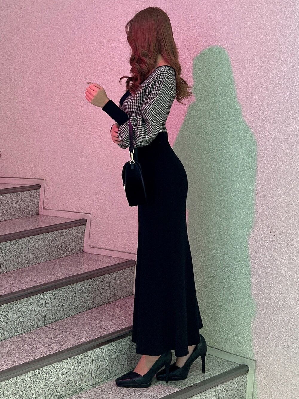 ブラック系のワンピース、ブラック系のパンプス、ブラック系のショルダーバッグを着用したレディースの冬コーディネートの3枚目の写真