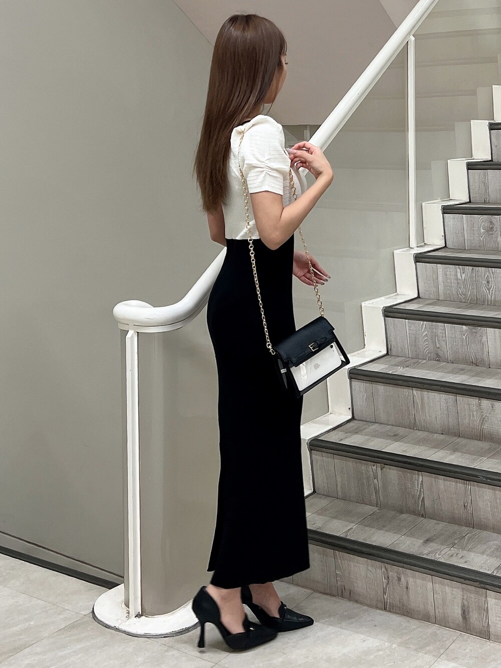 ブラック系のハンドバッグ、ホワイト系のワンピース、ブラック系のパンプスを着用したレディースの春コーディネートの3枚目の写真