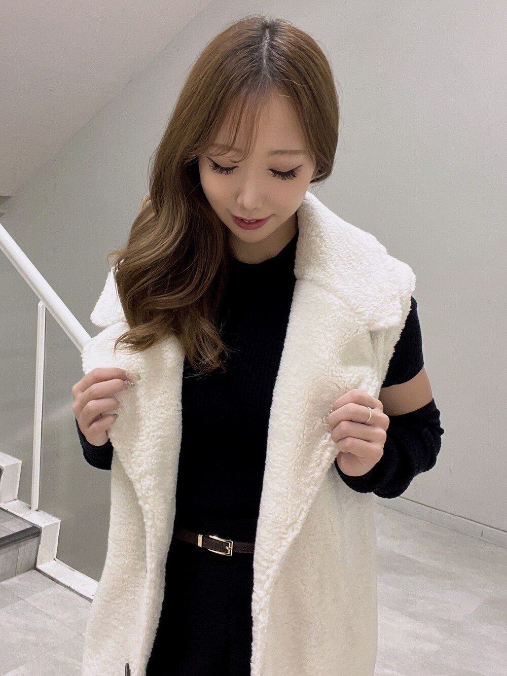 ブラック系のニット/セーター、ホワイト系のベスト、ブラック系のブーツを着用したレディースの秋コーディネートの4枚目の写真