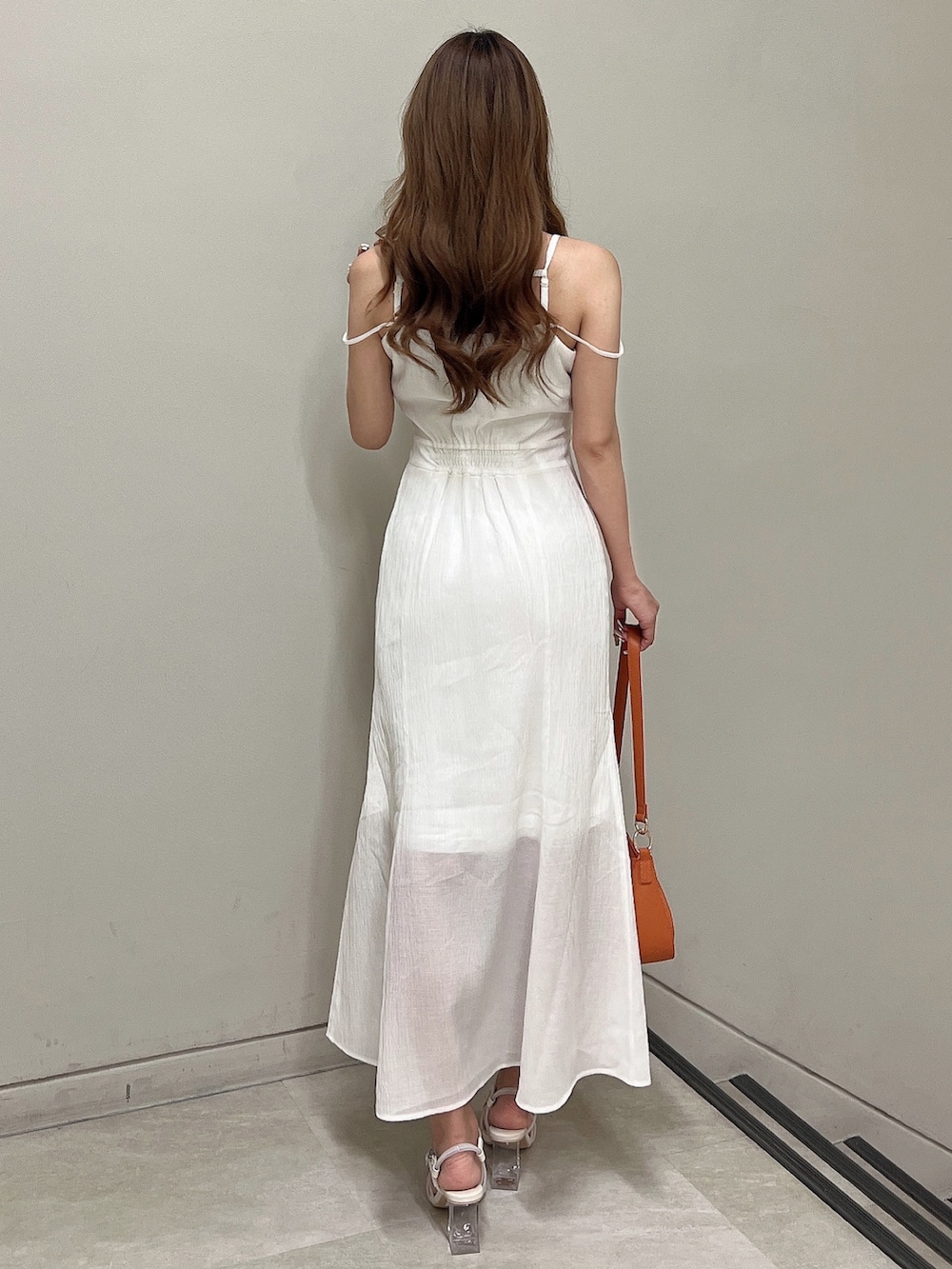 ホワイト系のワンピース、ホワイト系のサンダル、オレンジ系のハンドバッグを着用したレディースの夏コーディネートの4枚目の写真