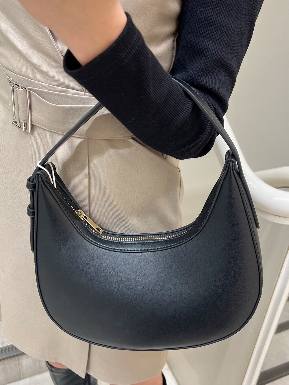 ベージュ系のワンピース、ブラック系のブーツ、ブラック系のハンドバッグを着用したレディースの冬コーディネートの6枚目の写真