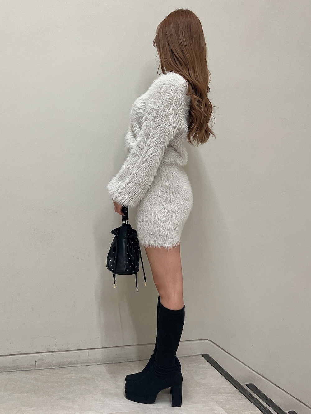 グレー系のワンピース、ブラック系のハンドバッグ、ブラック系のブーツを着用したレディースの秋コーディネートの5枚目の写真