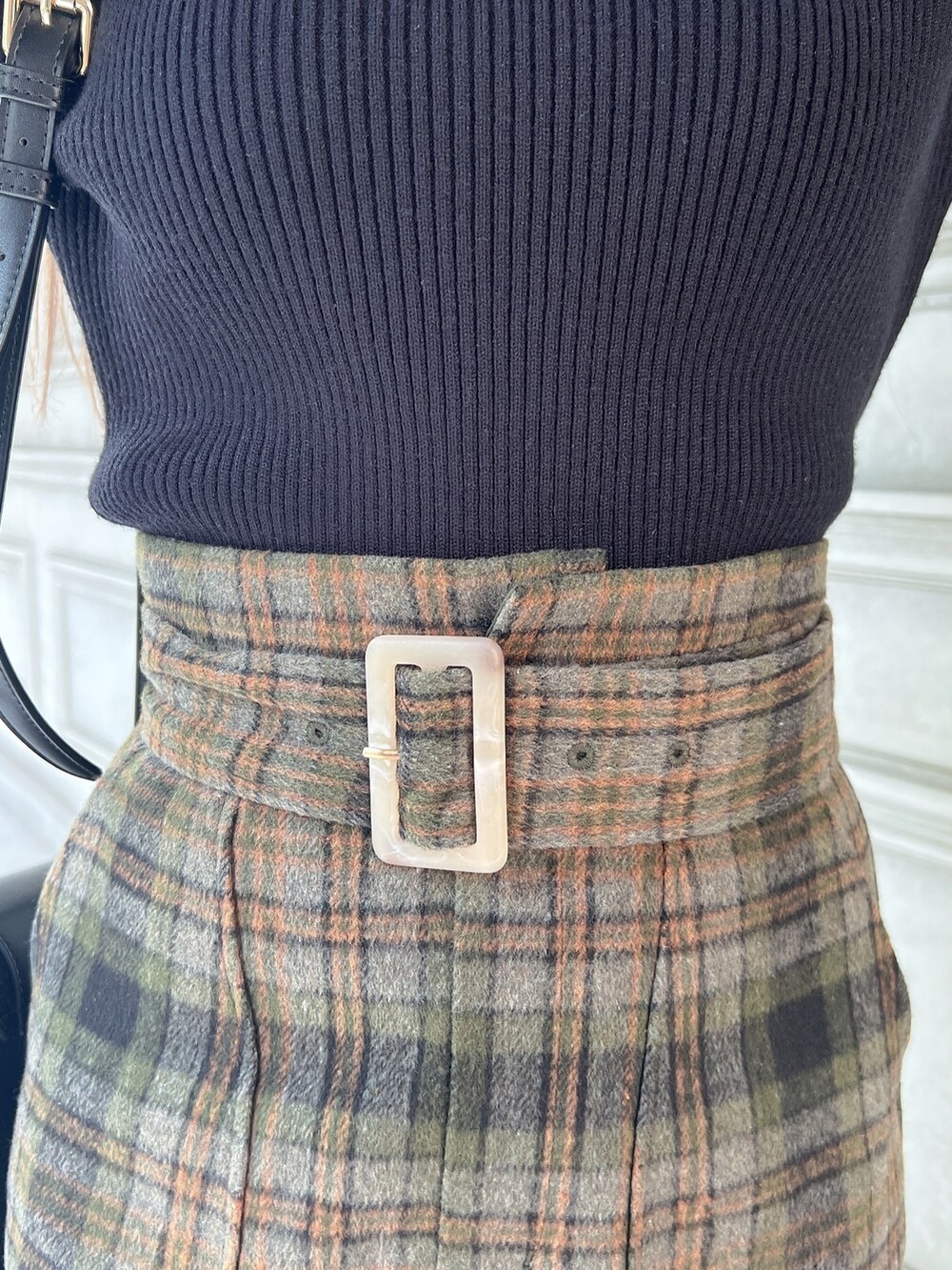 ブラック系のニット/セーター、グリーン系のスカート、ブラック系のショルダーバッグを着用したレディースの秋コーディネートの5枚目の写真