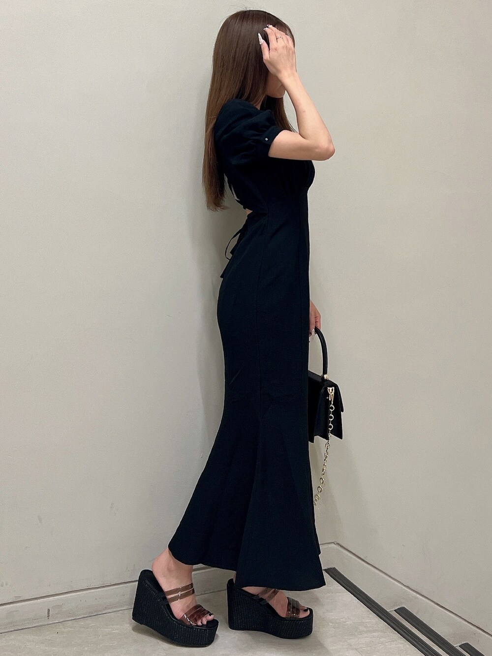 ブラック系のワンピース、ブラック系のサンダル、ブラック系のハンドバッグを着用したレディースの春コーディネートの3枚目の写真