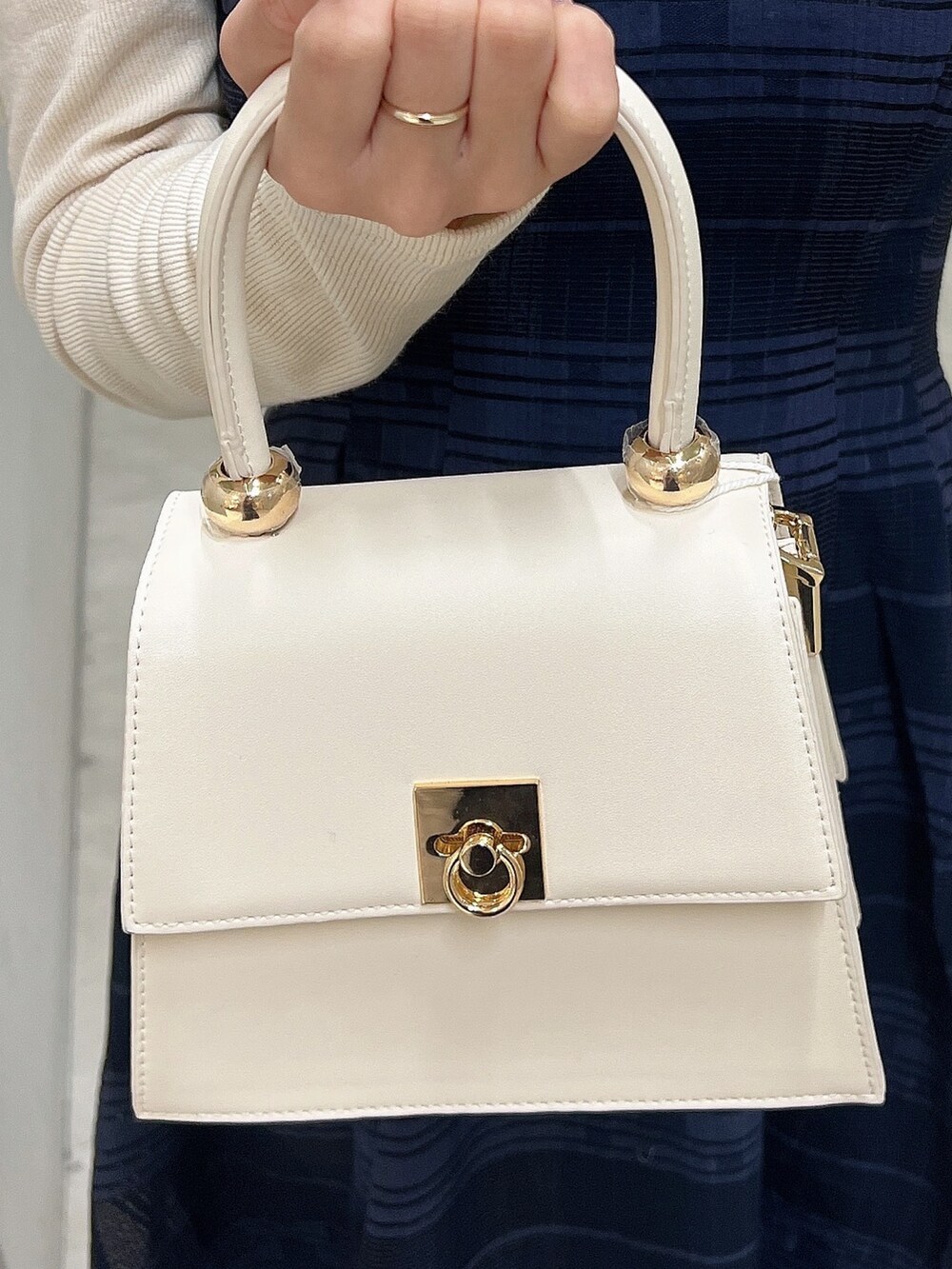 ホワイト系のパンプス、ブルー系のワンピース、ホワイト系のハンドバッグを着用したレディースの冬コーディネートの7枚目の写真