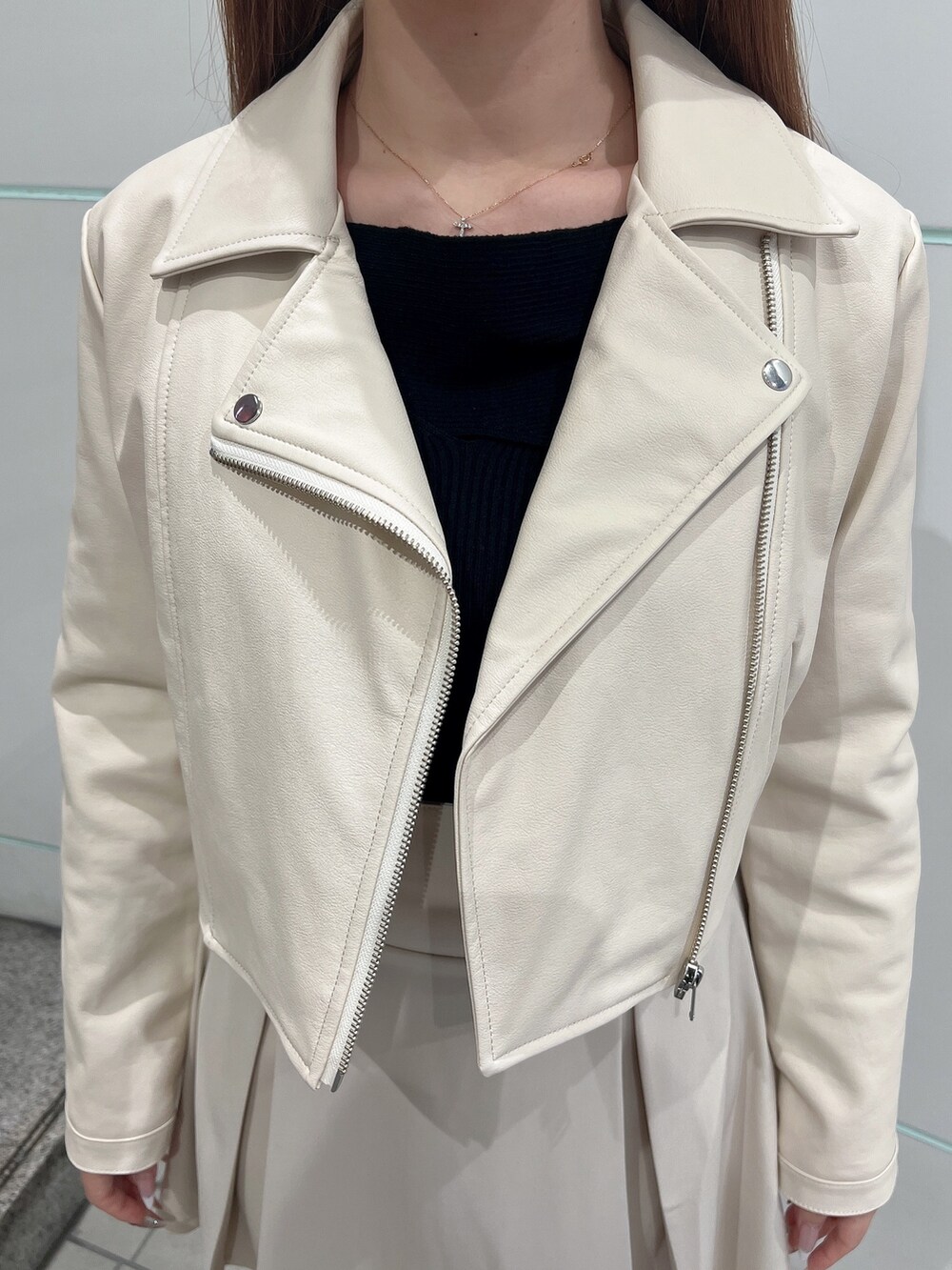 ホワイト系のライダースジャケット、ホワイト系のスカート、ブラック系のニット/セーターを着用したレディースの冬コーディネートの7枚目の写真