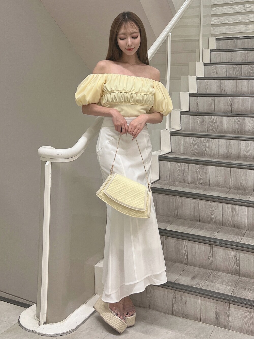 イエロー系のシャツ/ブラウス、ホワイト系のスカート、イエロー系のハンドバッグを着用したレディースの春コーディネートの2枚目の写真