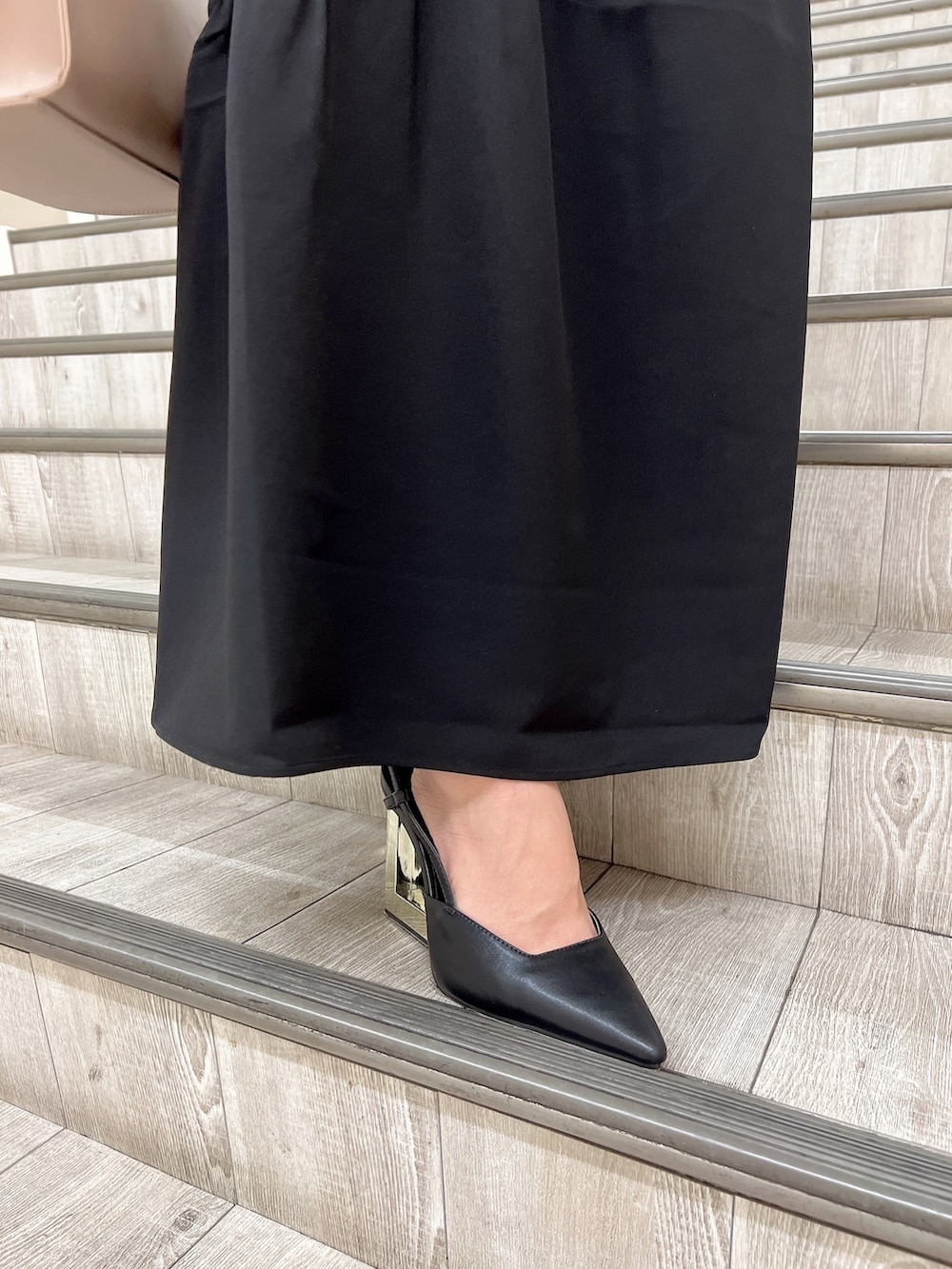 ブラック系のワンピース、ベージュ系のハンドバッグ、ブラック系のサンダルを着用したレディースの秋コーディネートの6枚目の写真