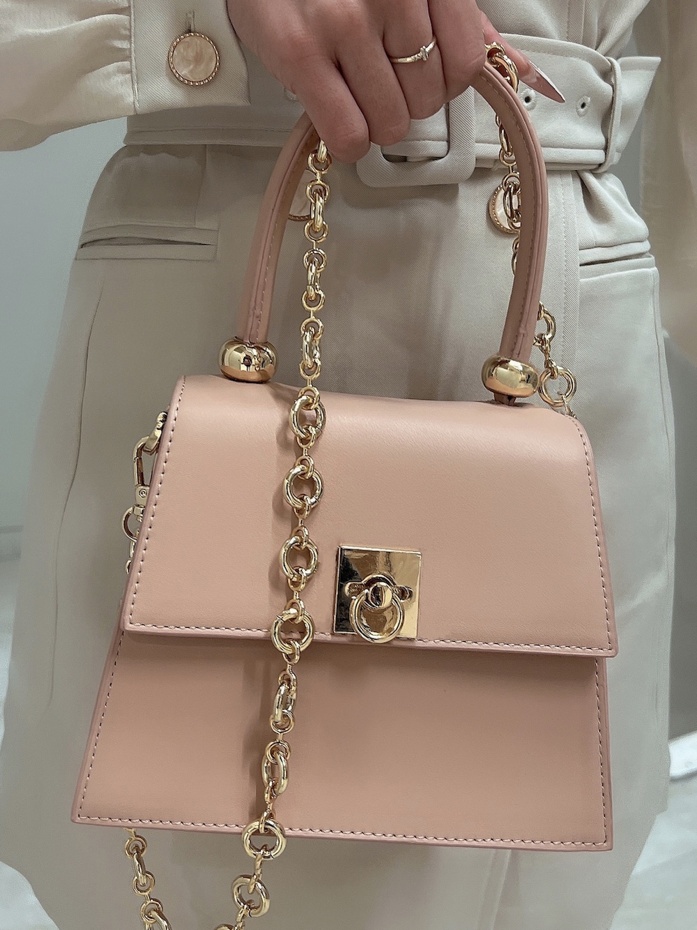 ホワイト系のワンピース、ピンク系のハンドバッグ、ホワイト系のブーツを着用したレディースの冬コーディネートの6枚目の写真