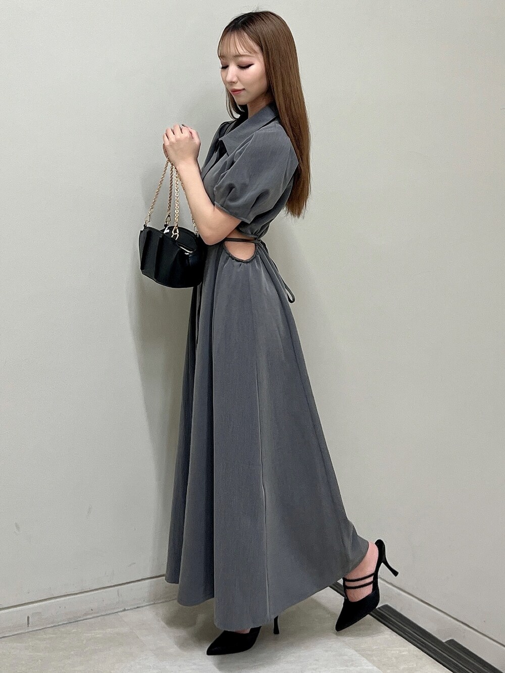 グレー系のワンピース、ブラック系のパンプス、ブラック系のハンドバッグを着用したレディースの春コーディネートの3枚目の写真