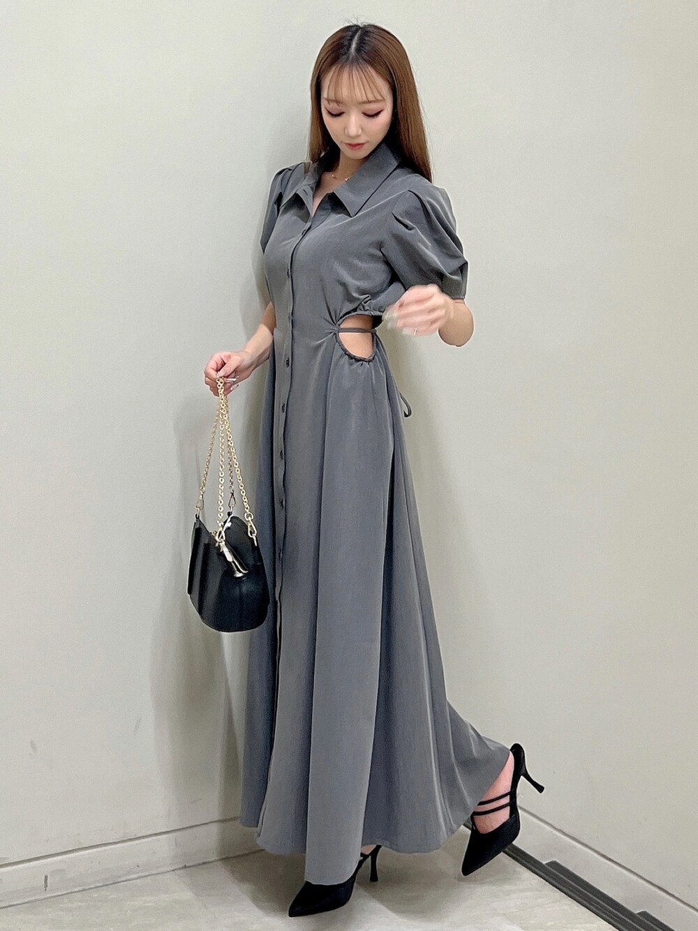 グレー系のワンピース、ブラック系のパンプス、ブラック系のハンドバッグを着用したレディースの春コーディネートの2枚目の写真