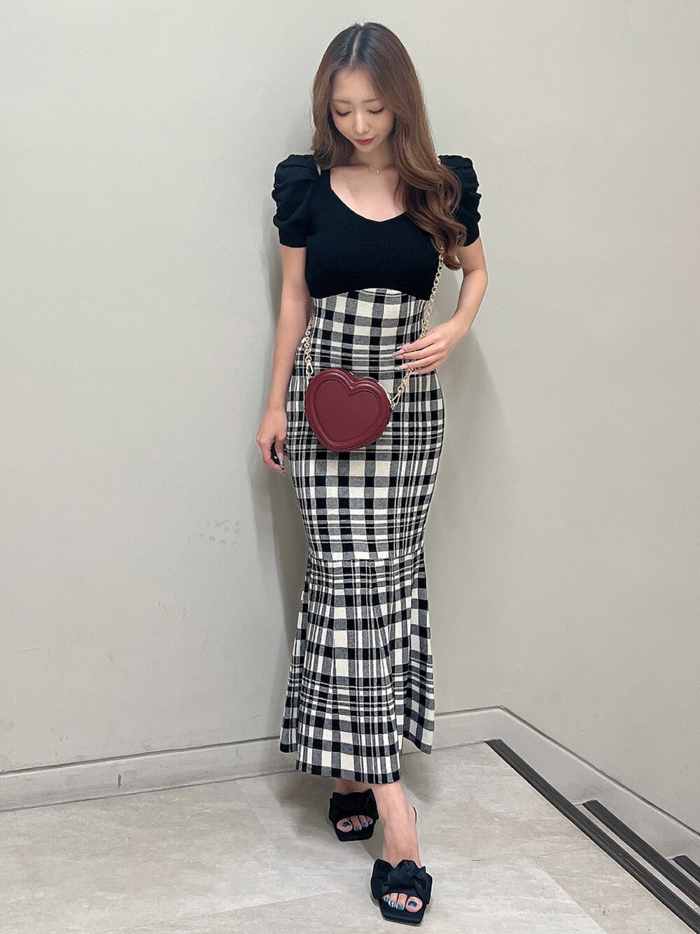 レッド系のショルダーバッグ、ブラック系のワンピース、ブラック系のサンダルを着用したレディースの夏コーディネートの2枚目の写真