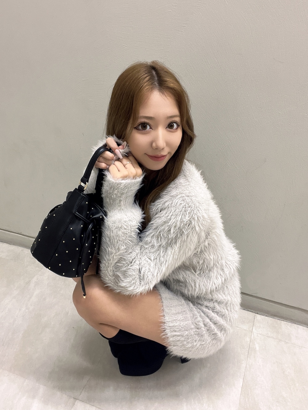 グレー系のワンピース、ブラック系のハンドバッグ、ブラック系のブーツを着用したレディースの秋コーディネートの7枚目の写真