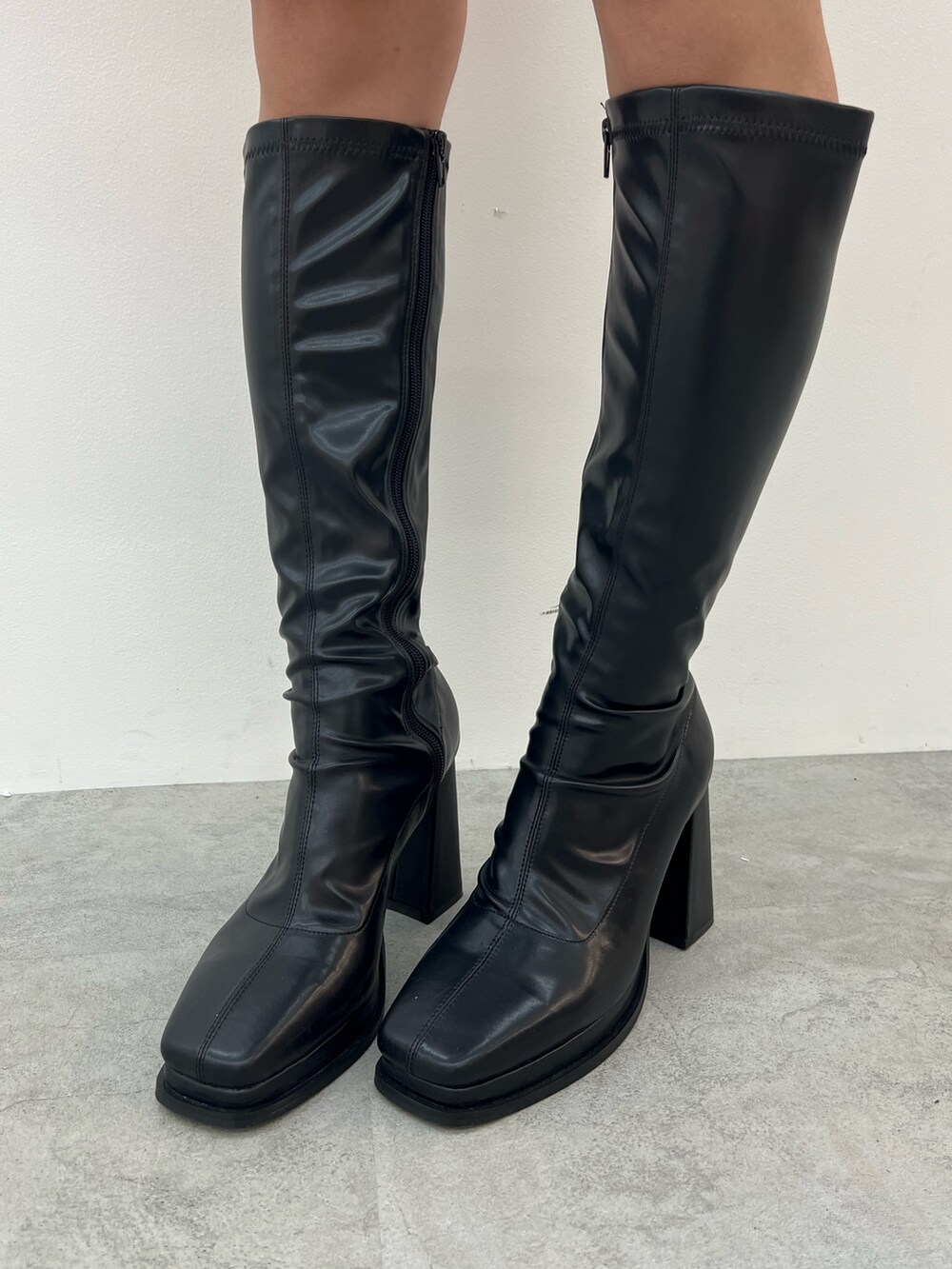 ブラック系のスウェット、グリーン系のハンドバッグ、ブラック系のブーツを着用したレディースの夏コーディネートの7枚目の写真