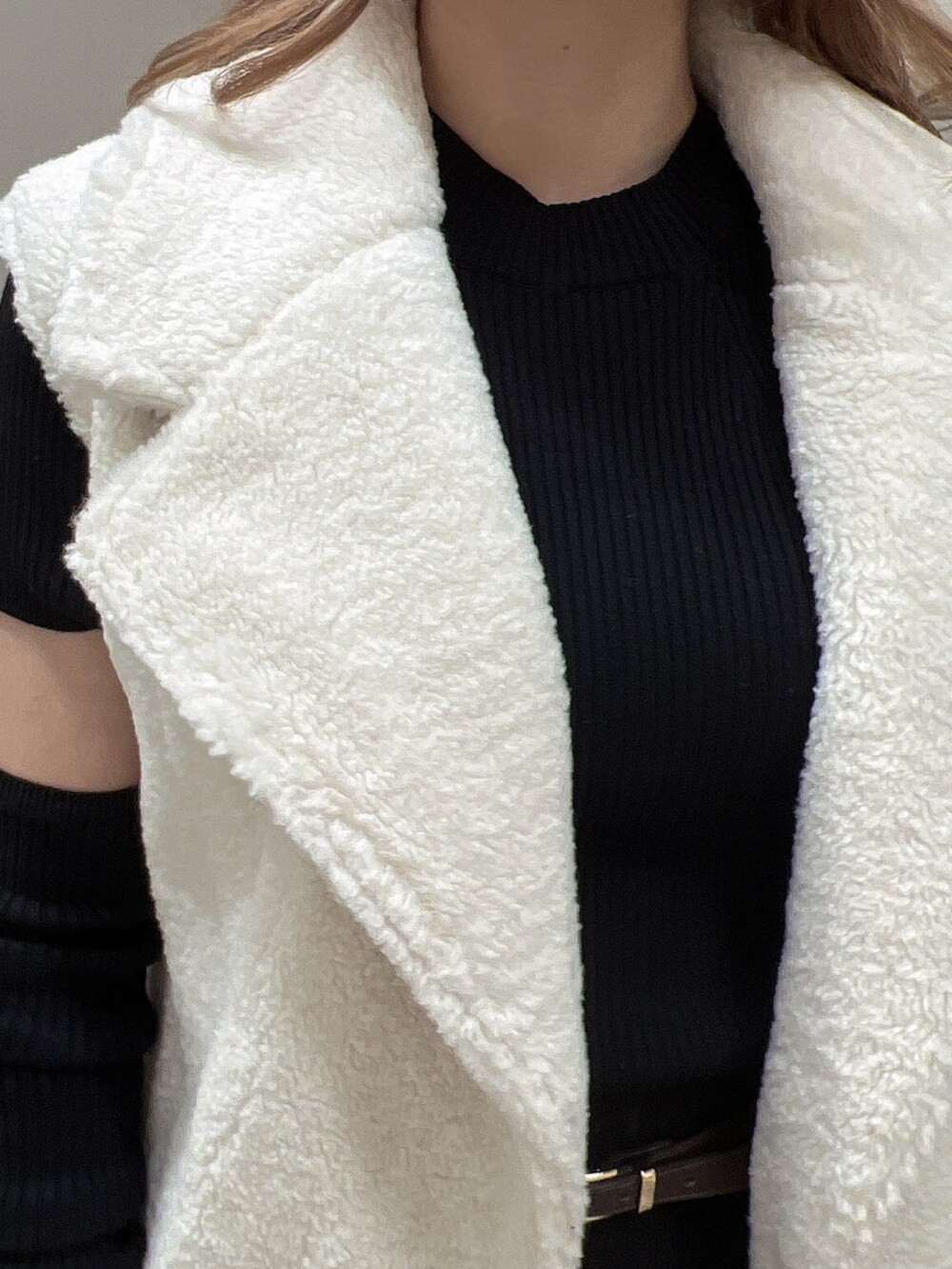 ブラック系のニット/セーター、ホワイト系のベスト、ブラック系のブーツを着用したレディースの秋コーディネートの7枚目の写真