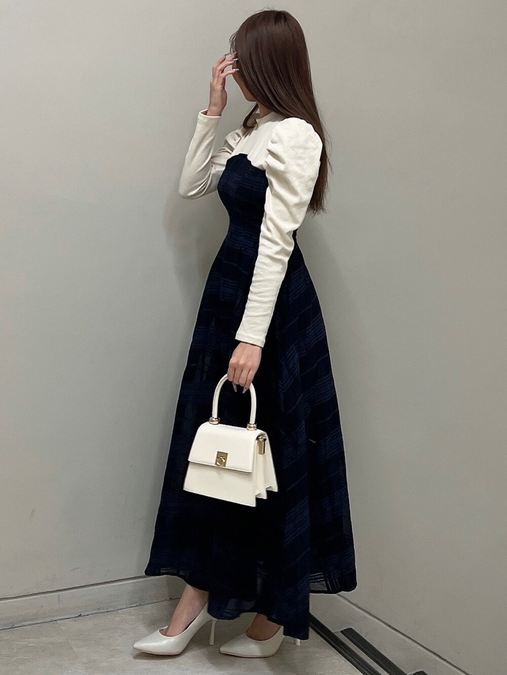 ホワイト系のパンプス、ブルー系のワンピース、ホワイト系のハンドバッグを着用したレディースの冬コーディネートの3枚目の写真