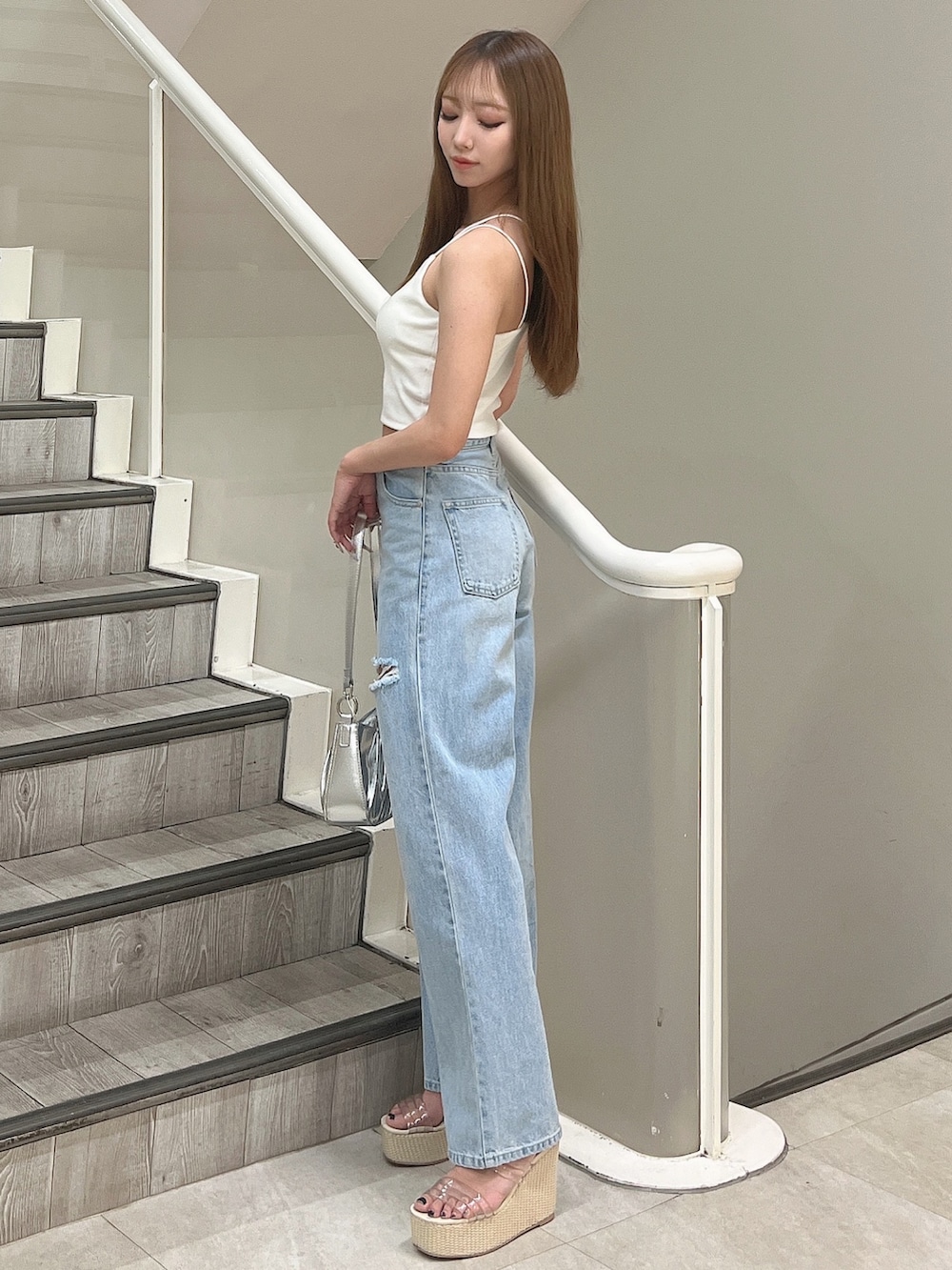 ホワイト系のキャミソール、ブルー系のデニムパンツ、シルバー系のハンドバッグを着用したレディースの春コーディネートの3枚目の写真