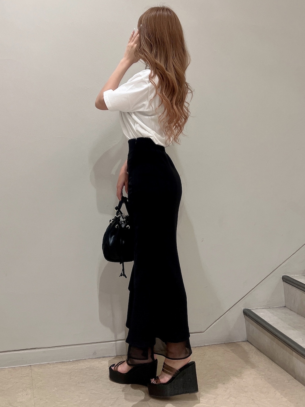 ホワイト系のTシャツ/カットソー、ブラック系のスカート、ブラック系のハンドバッグを着用したレディースの夏コーディネートの2枚目の写真