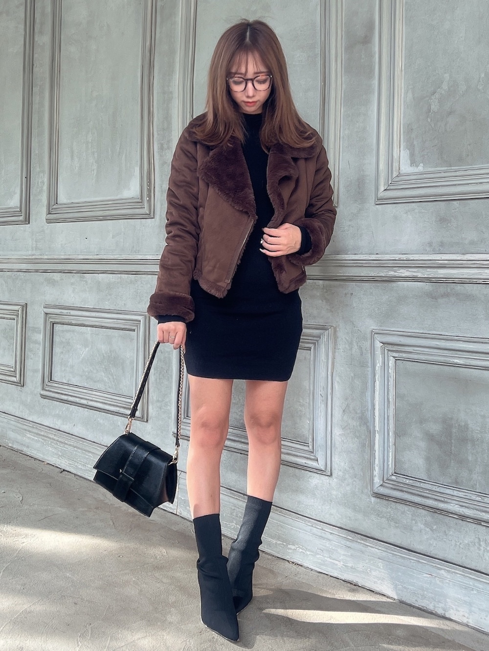 ブラック系のワンピース、ブラック系のハンドバッグ、ブラック系のブーツを着用したレディースの秋コーディネートの2枚目の写真