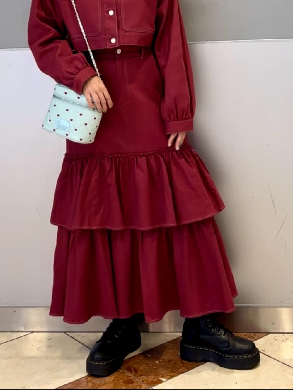 レッド系のワンピース、ブルー系のショルダーバッグ、ブラック系のネックレスを着用したレディースの秋コーディネートの8枚目の写真