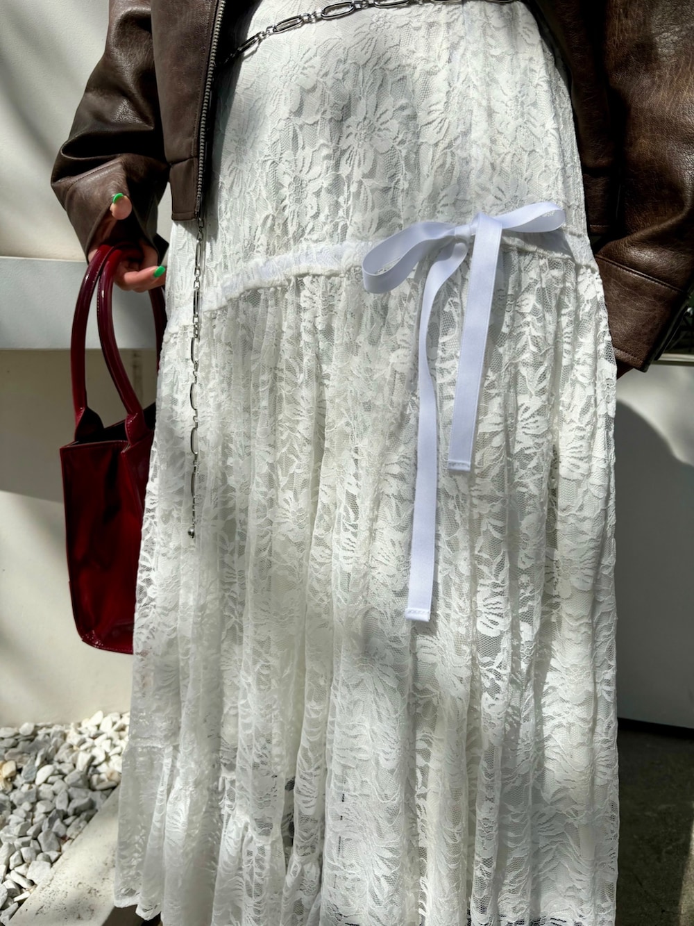 レッド系のハンドバッグ、レッド系のパンプス、ブラウン系のブルゾンを着用したレディースの夏コーディネートの8枚目の写真