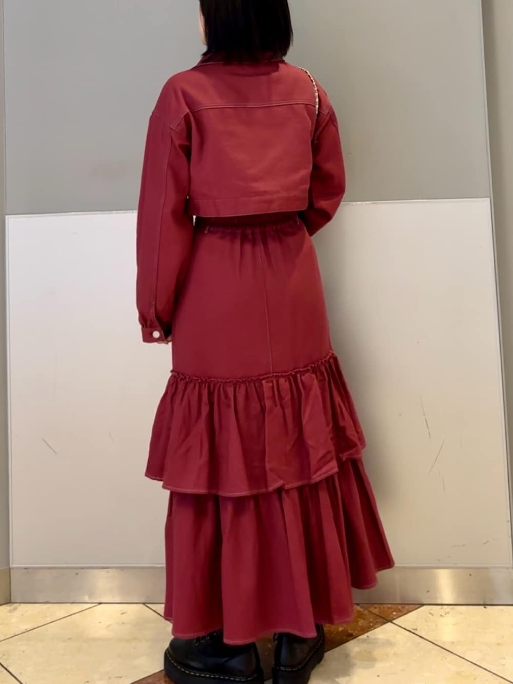 レッド系のワンピース、ブルー系のショルダーバッグ、ブラック系のネックレスを着用したレディースの秋コーディネートの4枚目の写真