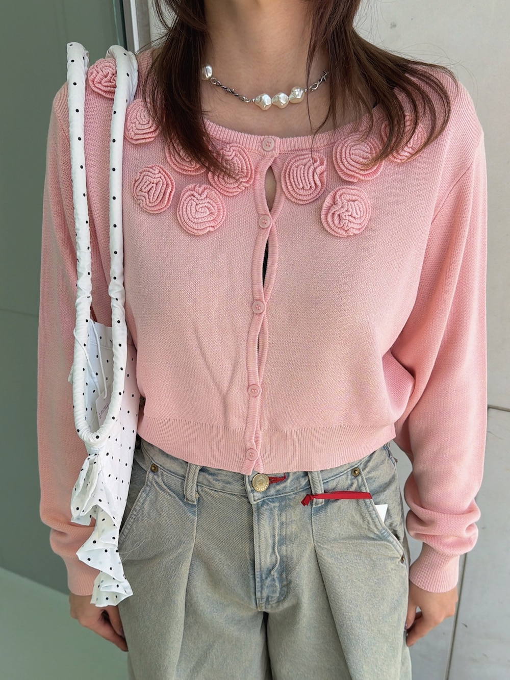 ピンク系のニット/セーター、ホワイト系のトートバッグ、ブルー系のデニムパンツを着用したレディースの春コーディネートの9枚目の写真