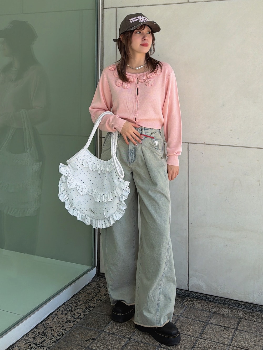 ピンク系のニット/セーター、ホワイト系のトートバッグ、ブルー系のデニムパンツを着用したレディースの春コーディネートの2枚目の写真