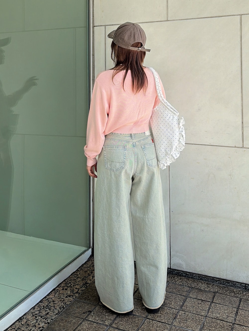 ピンク系のニット/セーター、ホワイト系のトートバッグ、ブルー系のデニムパンツを着用したレディースの春コーディネートの3枚目の写真