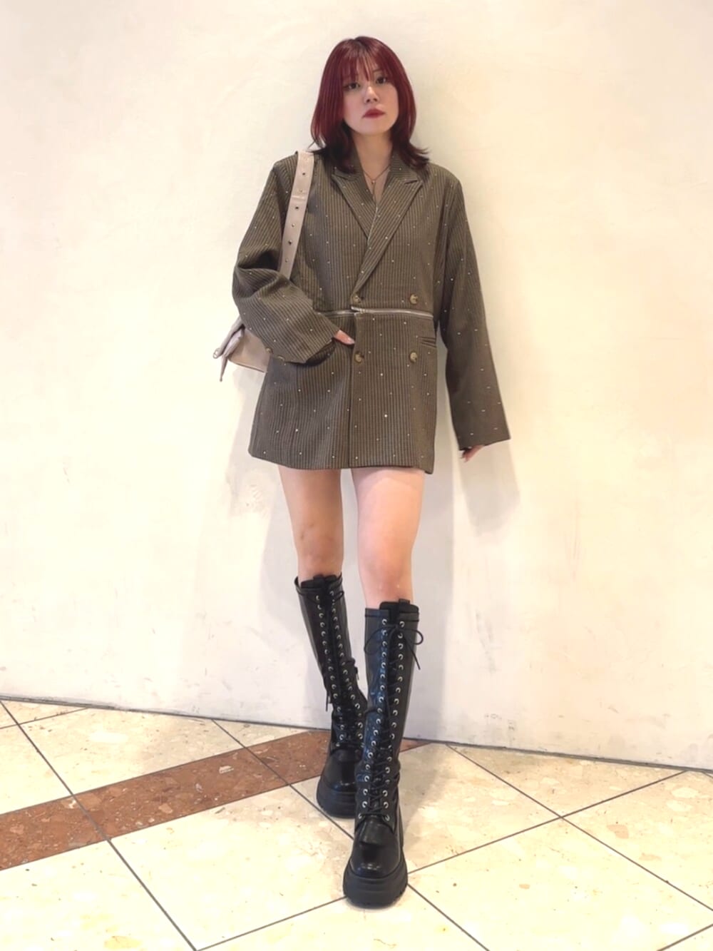 ブラック系のブーツ、ピンク系のショルダーバッグ、グレー系のテーラードジャケットを着用したレディースの秋コーディネートの2枚目の写真