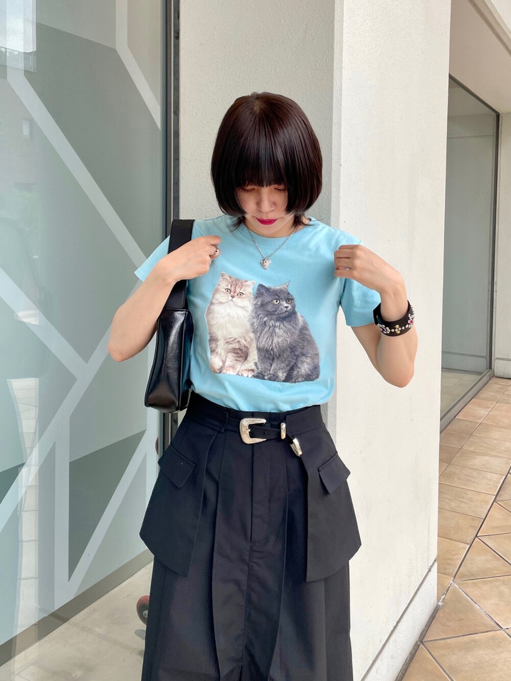 ブルー系のTシャツ/カットソー、ブラック系のスカート、シルバー系のハンドバッグを着用したレディースの春コーディネートの5枚目の写真