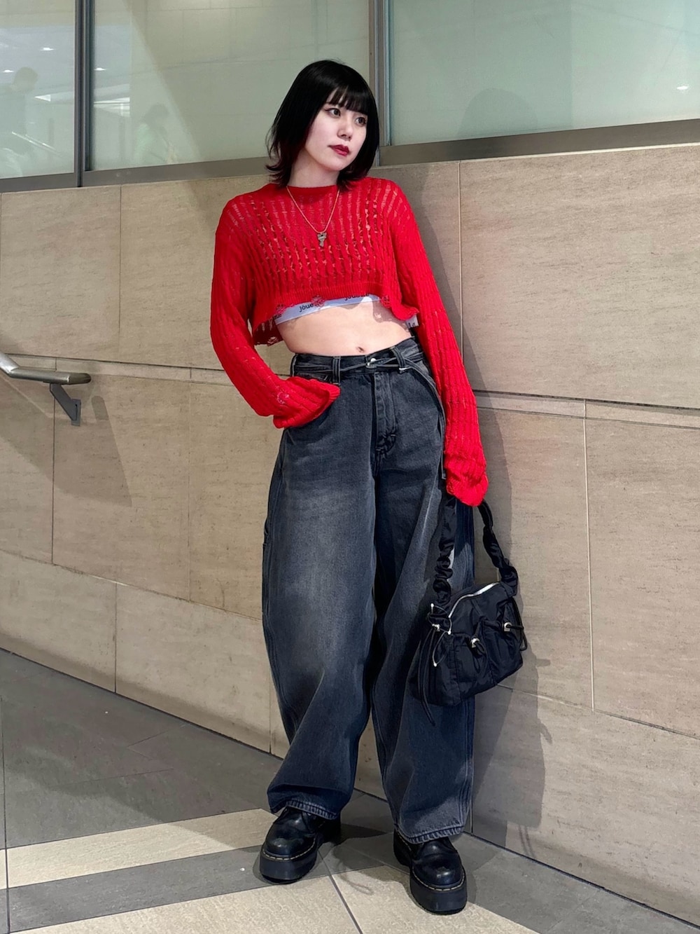 ブラック系のデニムパンツ、ブラック系のショルダーバッグ、レッド系のニット/セーターを着用したレディースの春コーディネートの2枚目の写真