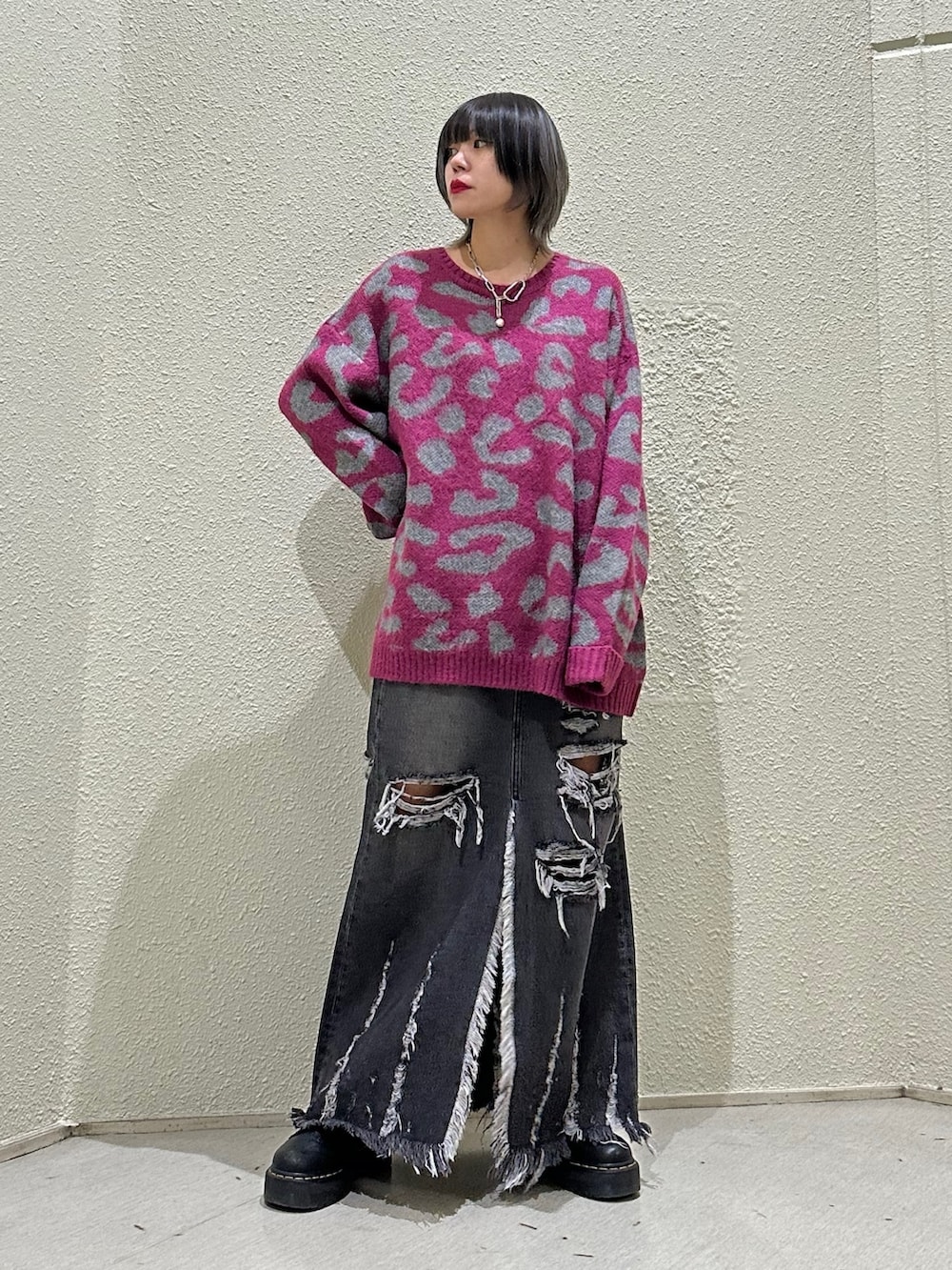 ピンク系のニット/セーター、ブラック系のデニムスカートを着用したレディースの冬コーディネートの2枚目の写真